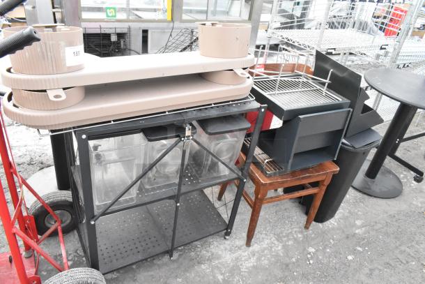 Lot of items including a tan chair, black shelving unit with containers, and various accessories. Mix of metal and wood.