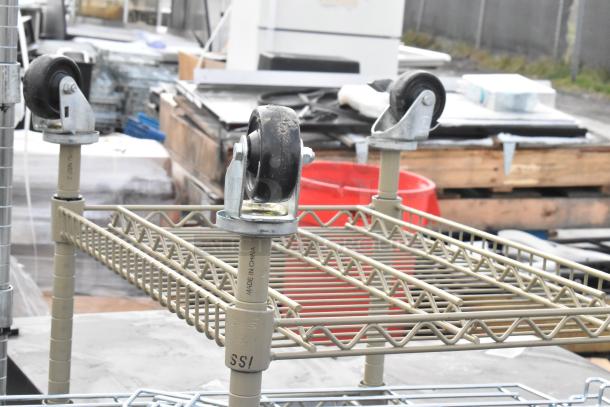 Metal shelving unit with robust casters, featuring two tiers and "Made in China" mark, on an outdoor surface.