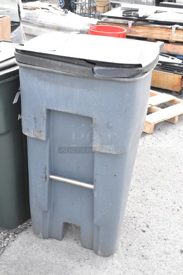 Gray outdoor poly trash can with lid, visible wear, metal handle. Auction includes two trash cans for bid multiplier.