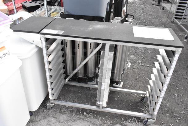 Metal commercial double pan rack on casters; multiple shelves, sturdy design, used for kitchen or bakery storage.