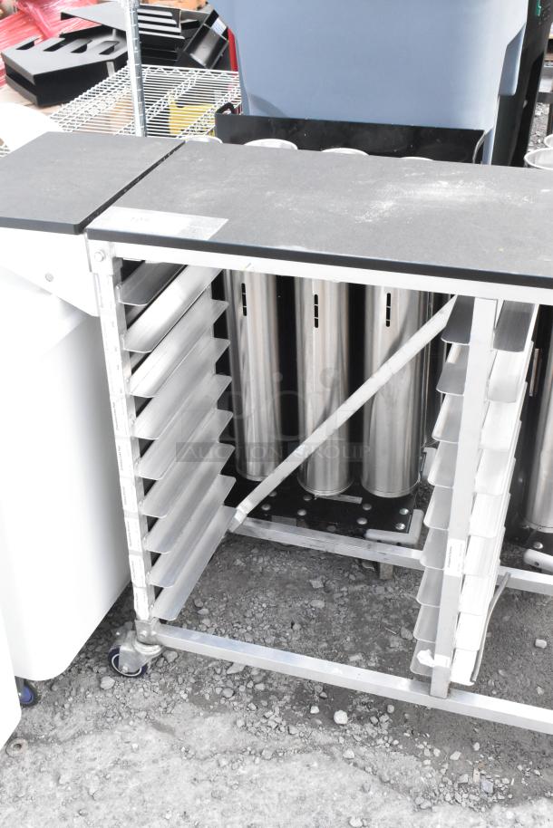 Metal commercial double pan rack on sturdy casters, in used condition. Features side slots for pans, ideal for kitchen use.