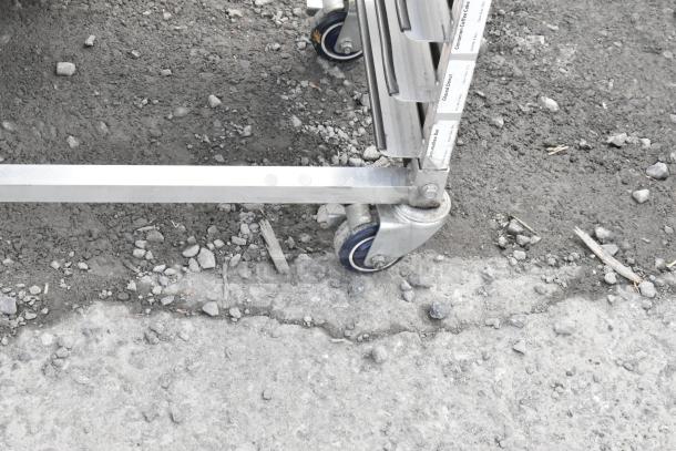 Metal commercial double pan rack on sturdy casters, showing labels with bakery item names, ideal for bakeries or kitchens.