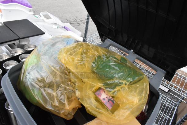 Two poly trash cans containing baskets and floor mats; includes contents in plastic bags; auction lot doubles bid value.