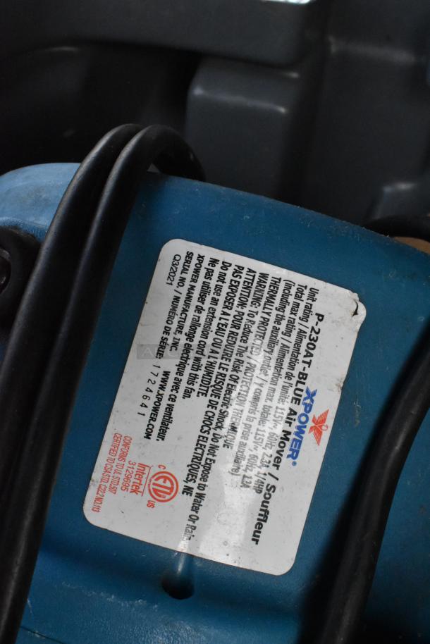Poly trash can with contents including a blue XPOWER fan and a basket. Fan label shows model P-230AT with safety warnings.