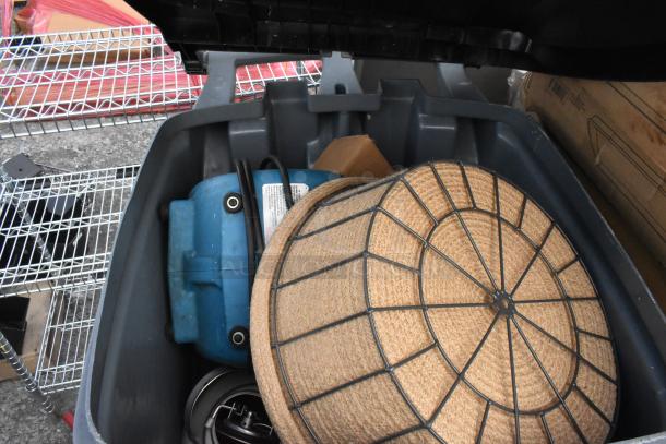 Poly trash can with a blue fan, woven basket, and assorted contents inside, lid open, showing conditions and items.