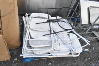 Stack of white folding chairs with a black metal basket stand, labeled as brand new with scratch and dent condition.