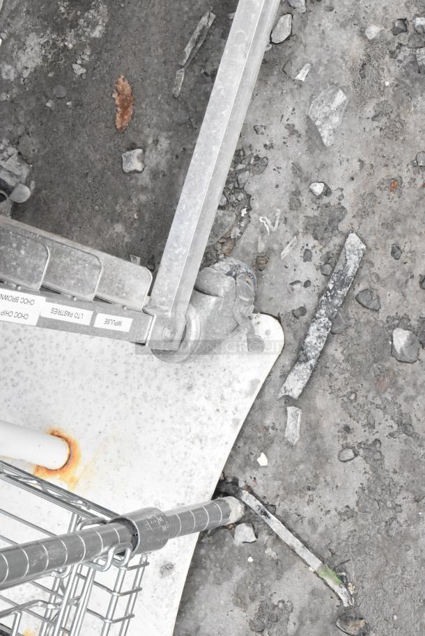 Metal commercial double pan transport rack on casters, includes labeled metal baking pans. Tags visible. Used condition.