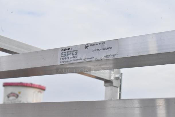 Metal commercial pan transport rack with commercial casters, labeled "KELMAX by SPG," Model No. 4H7133, NSF certified.