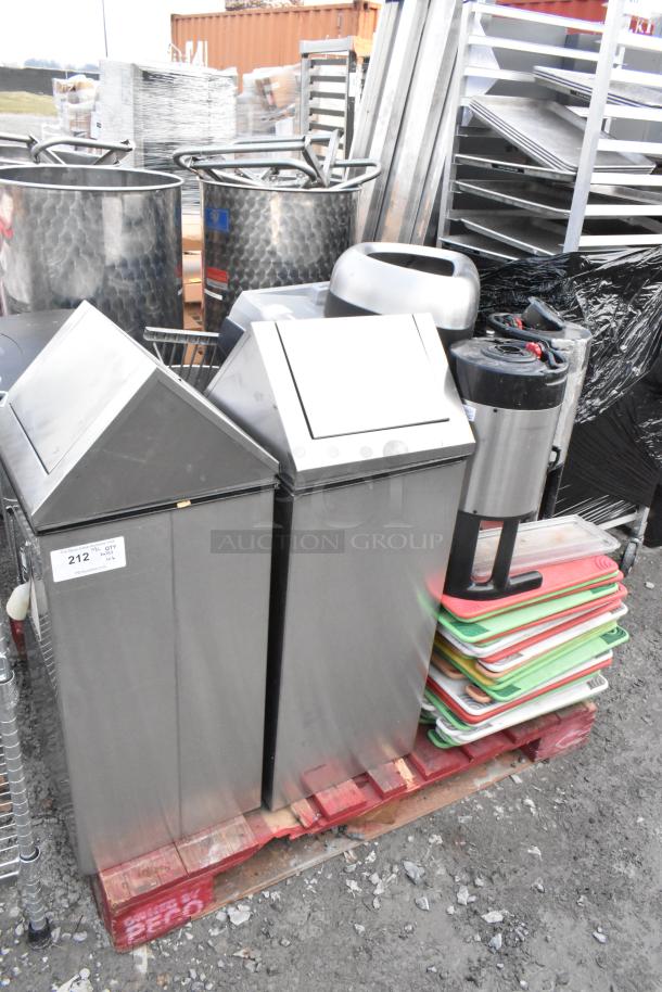 Pallet of various items including stainless trash can shells, stacked cutting boards, and a hot beverage dispenser.