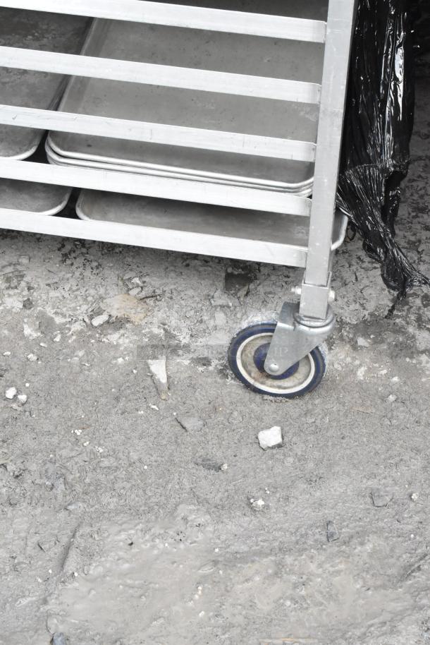 Metal pan transport rack on commercial casters, multiple shelves, durable metal construction, used condition.