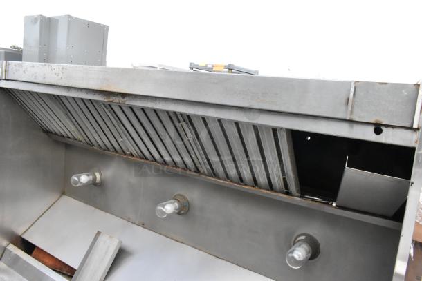 8' metal commercial grease hood with filters and integrated lights, showing signs of use and slight discoloration.