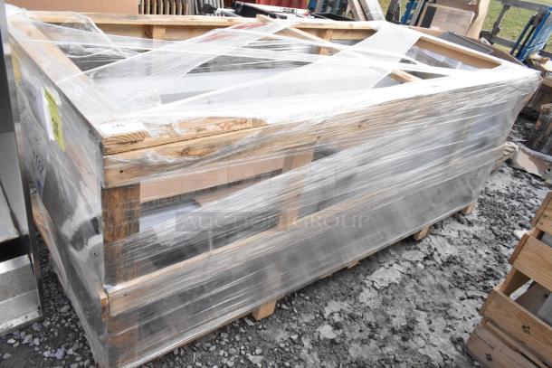 Brand new Regency 600S31824218 stainless steel 3 bay sink with dual drain boards, no legs, partially wrapped on a pallet.