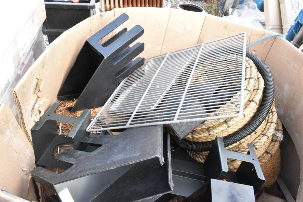 Pallet with various items including metal racks, coiled rope, and black plastic holders, in fair condition.