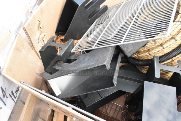 Pallet lot with metal grids, black brackets, rope, and a lid dispenser in a cardboard box; mixed condition.