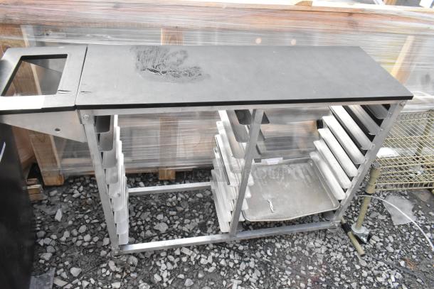 Metal commercial double pan transport rack with commercial casters, used condition, visible wear on top surface.