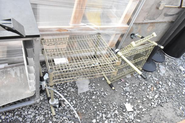 Two tan finish 2-tier wire shelving units on gravel surface. Shelves appear intact. Buyer must dismantle for shipping.