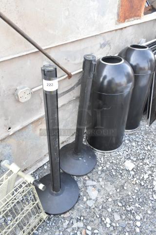 Two black stanchions and two black metal trash can shells, used condition, identification tag 222 visible on one stanchion.