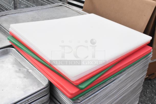 Alt text: "Stack of full-size and half-size metal baking pans with white, red, and green cutting boards on top. Auction lot of 180 items."