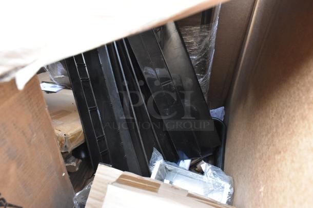 Box containing a variety of new scratch and dent items, including stainless steel mop sink parts, with packaging visible.