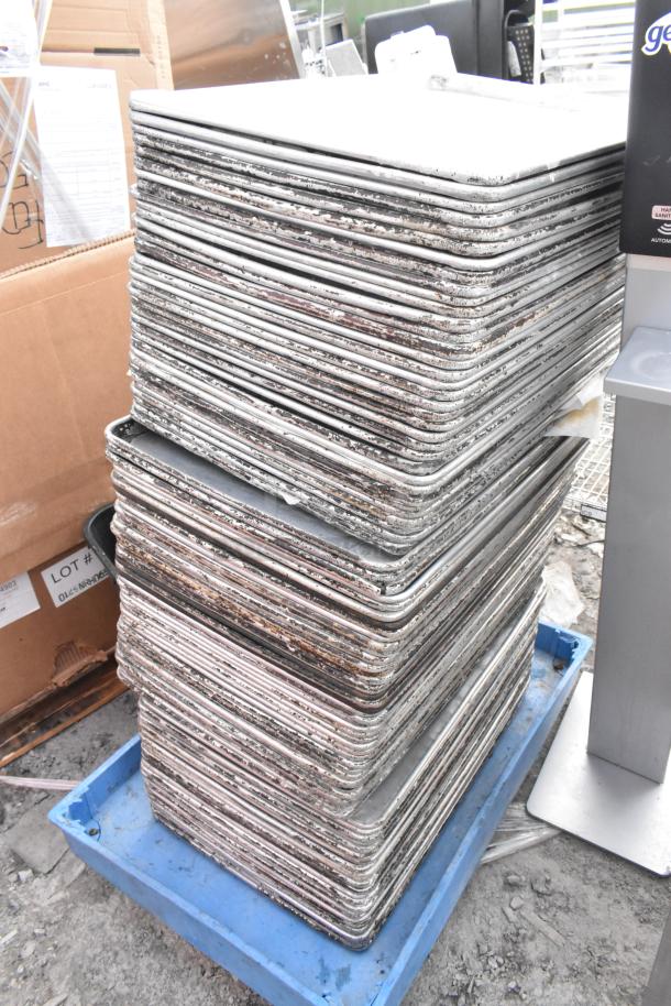 Stack of 95 full-size metal baking pans, showing signs of wear. Auction lot with 95 times your bid multiplier.