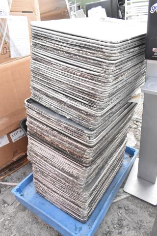 Stack of 95 full-size metal baking pans, showing signs of wear. Auction lot with 95 times your bid multiplier.