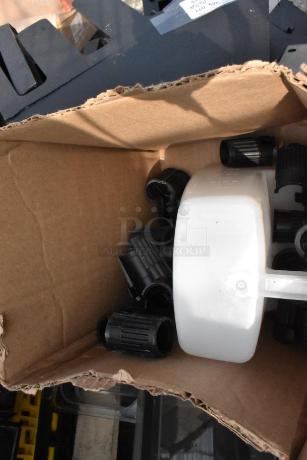 Pallet lot of miscellaneous items, including black lid dispensers, in used condition, packed in a cardboard box.