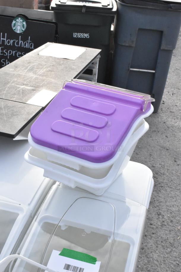 Eight brand new clear and white poly bins, some with purple lids, labeled for ingredients. Ideal for storage; slight imperfections.