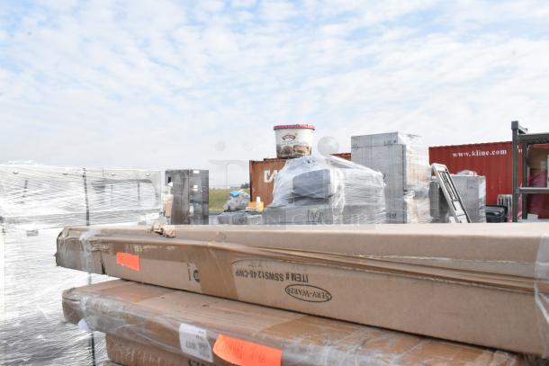 Boxes and wrapped pallets of scratch and dent items, including Metro and Vollrath shelving, in a warehouse yard.