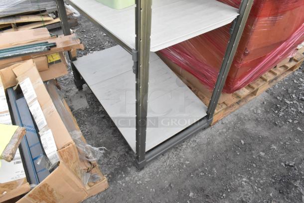 Four-tier shelving unit with metal frame and white shelves, holding assorted contents. Appears in used condition.