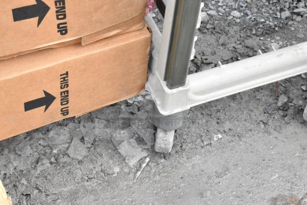 Metal commercial pan transport rack on casters, shown next to boxes labeled "This End Up." Ideal for kitchen use.