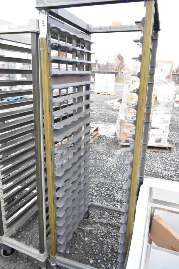 Metal commercial pan transport rack with multiple slots and sturdy commercial casters, in used condition.