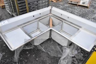 Brand new Steelton 3-compartment corner sink in 18-gauge stainless steel, features two drainboards, 18" x 18" x 12" bowls, no legs.