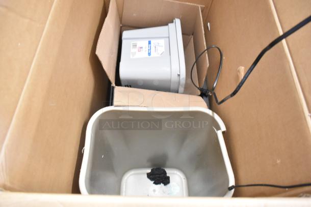 Lot of various items in a box, including a paper towel dispenser, keyboard, trash can, and security camera system, mixed condition.