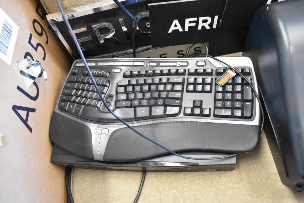 Lot of various items including a wireless keyboard, visible cables, and parts of a paper towel dispenser. Condition appears used.