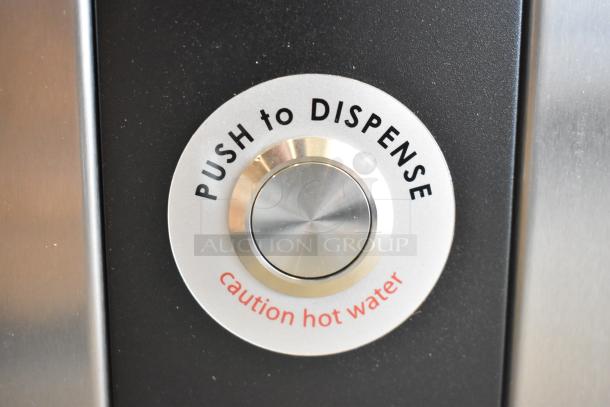 Close-up of "Push to Dispense" button on Grindmaster 1000665GM stainless steel hot water dispenser, cautioning hot water.