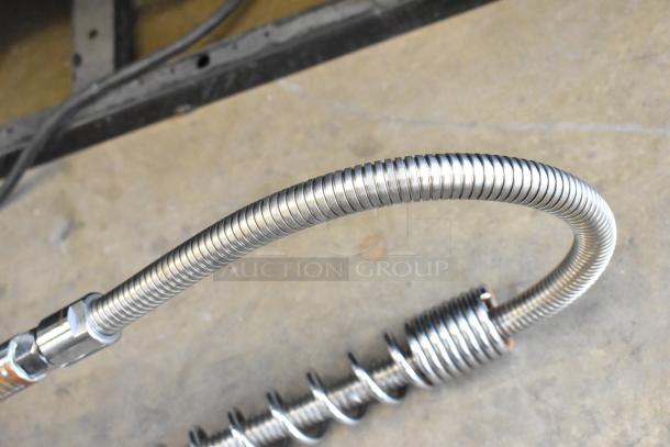 Metal faucet with flexible spray nozzle, coiled hose design, in good condition, ideal for kitchen or industrial use.