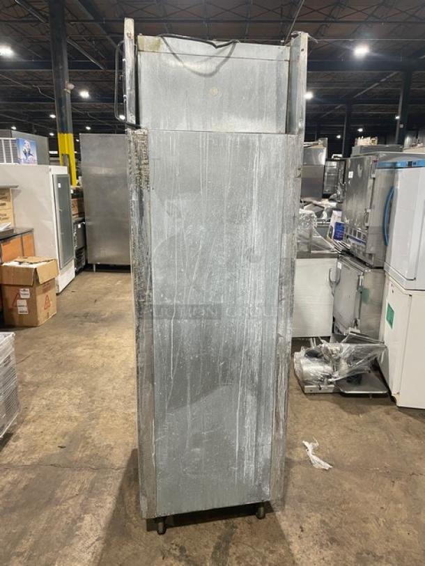 Delfield SMR1N-SH13 stainless steel two-door refrigerator, with wired oven rack, on casters, showing signs of wear.