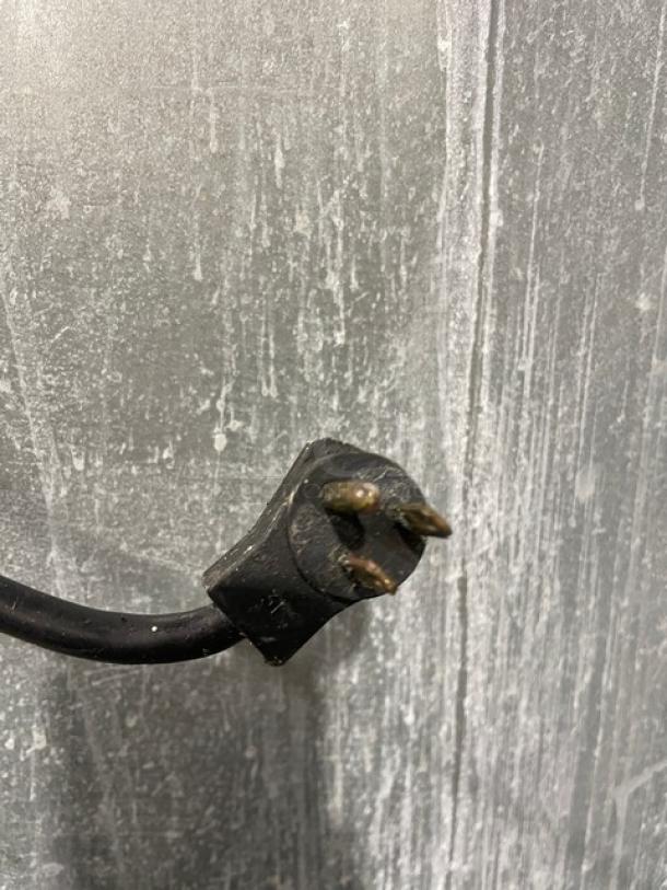 Close-up of a black three-prong plug, part of the Delfield SMR1N-SH13 refrigerator.