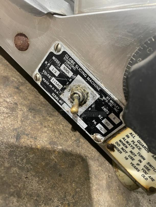 Globe 500L commercial stainless steel meat slicer, electric-powered, countertop model on legs. Features include visible control switch, model label showing Model 500L, 115V, 1/3 HP.