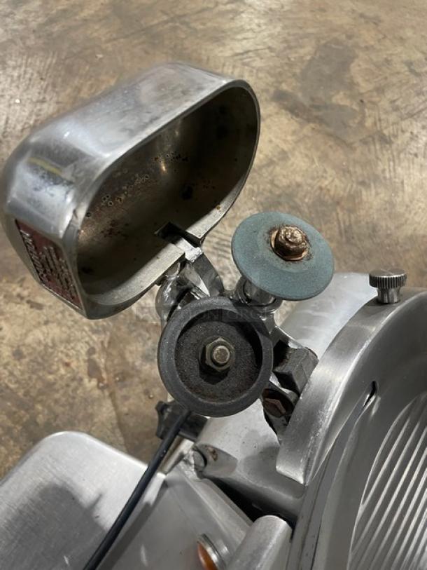 Globe 500L stainless steel electric deli slicer on legs, showing blade assembly. Heavy-duty, slightly used condition.