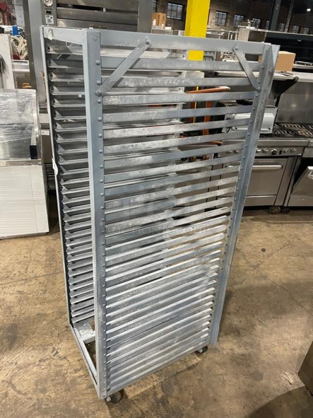 Commercial refrigerator/proofer rack on casters, metal construction, multiple shelf slots, good condition, industrial setting.