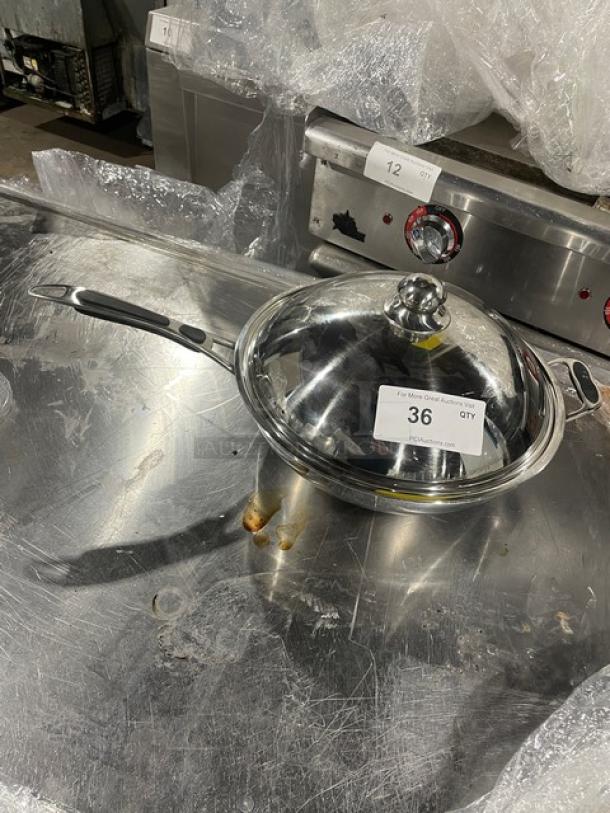 Commercial stainless steel kitchen pan with lid, featuring gray grip handle. Appears in used condition, auction tag "36."