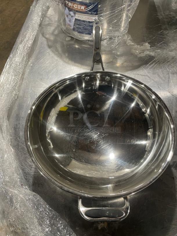 Stainless steel kitchen pan with lid, gray grip handle, commercial grade, pristine condition. Tri-ply design visible.