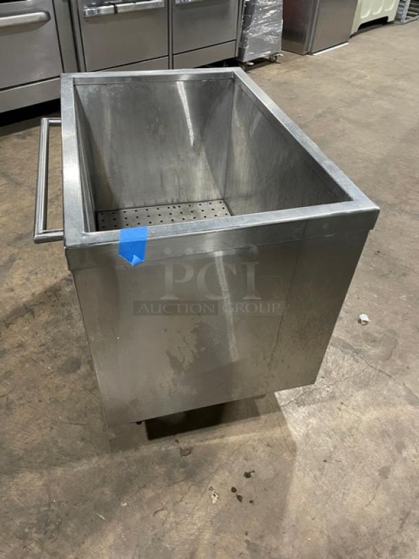 Commercial stainless steel portable ice bin on casters, used condition, features drainage grates and side handle for mobility.