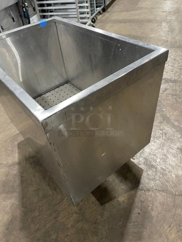Commercial stainless steel portable ice bin on casters, featuring deep basin, sturdy construction, and minor surface wear.