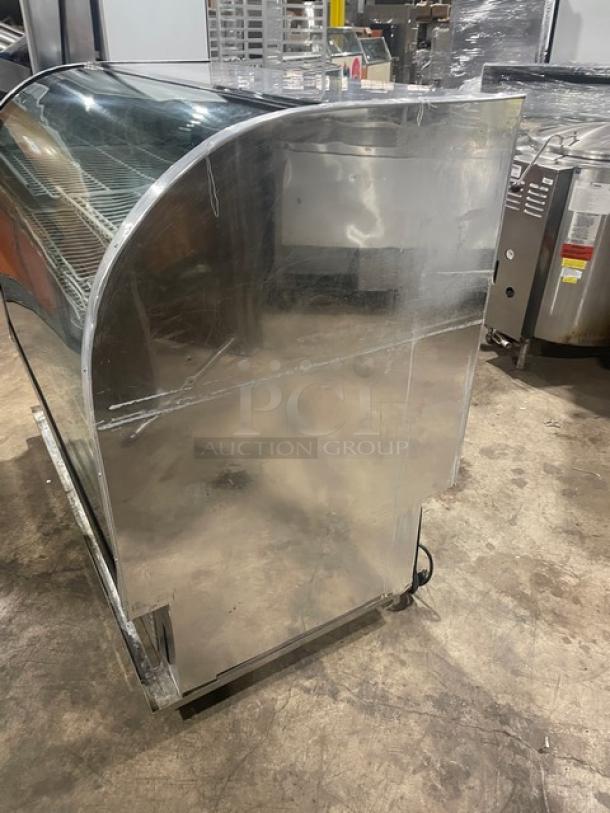 Marc stainless steel curved glass refrigerated bakery display case, multi-tier, poly-coated wire rack, sliding doors, on casters.