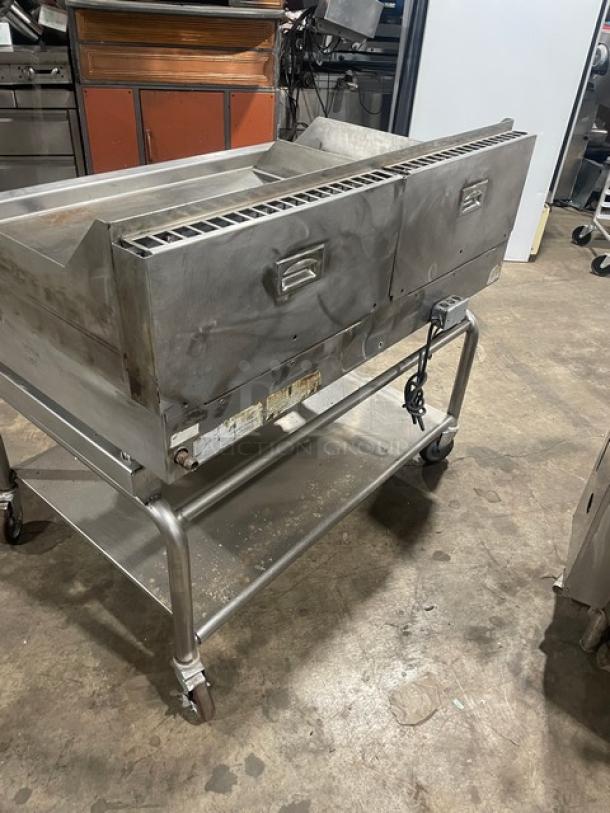 WoodStone stainless steel natural gas plancha griddle with back and side splash, on a single undershelf stand with casters.