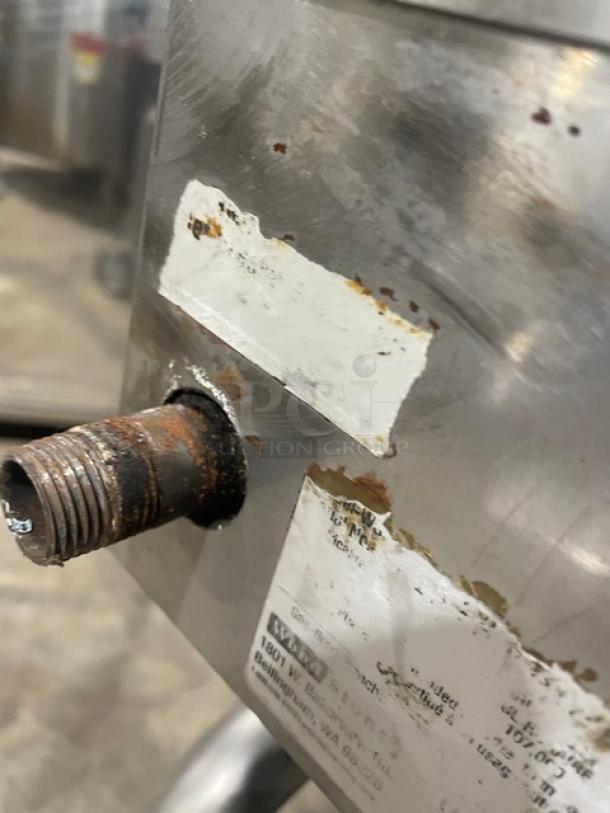 WoodStone stainless steel natural gas countertop plancha griddle with rust on fittings and worn labels, includes splash guards.