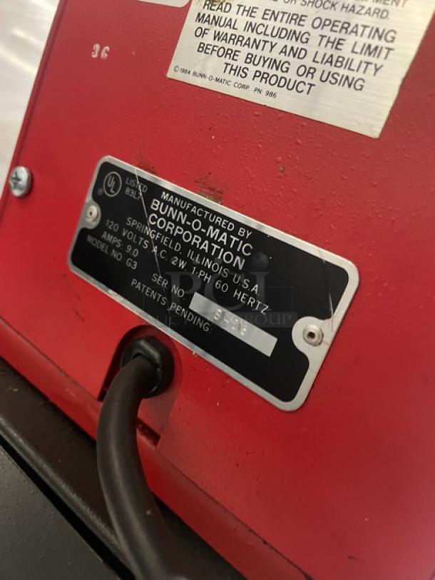 Bunn G3 commercial red bulk coffee grinder, electric powered, 120V, with manufacturer's label and serial number 8406 visible.