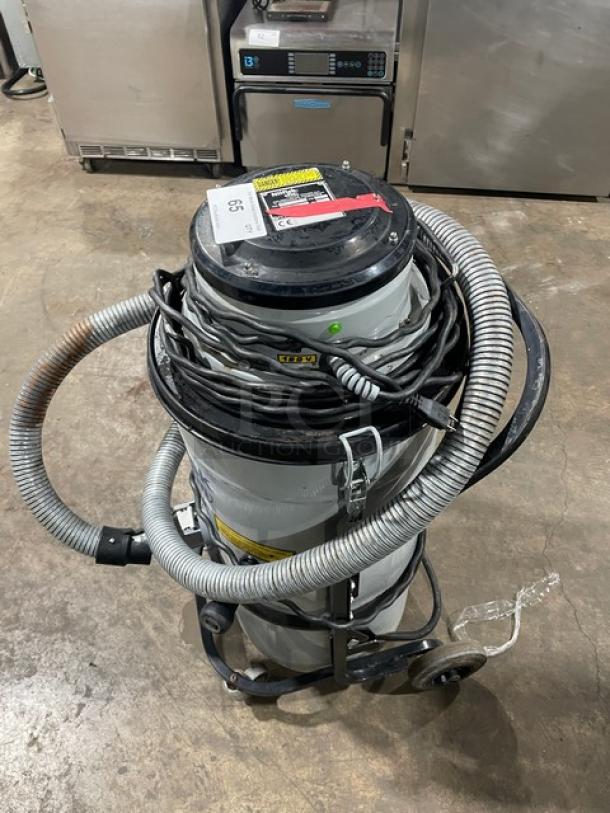 Nilfisk CFM Model 118 industrial vacuum cleaner, electric-powered, 120V, on casters, coiled hose, visible wear.